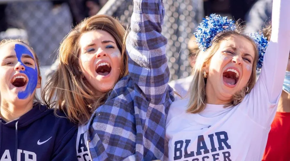 Due studentesse della Blair Academy festeggiano con le braccia alzate durante un evento sportivo.