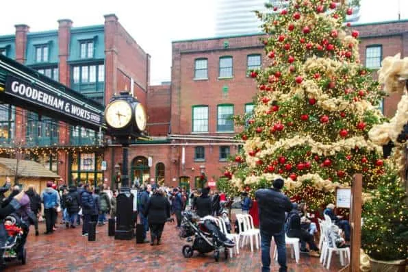 Gran árbol de Navidad decorado con luces en una plaza con personas y edificios