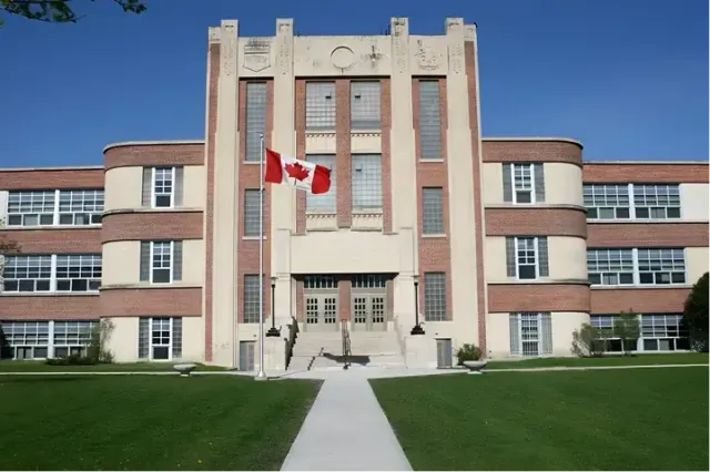 Edificio in mattoni di una high school canadese con la bandiera del Canada e prato antistante