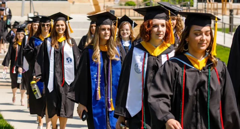 Un gruppo di diplomati del St Mary’s District & Vocational Collegiate Institute posa nel campus in abito accademico.