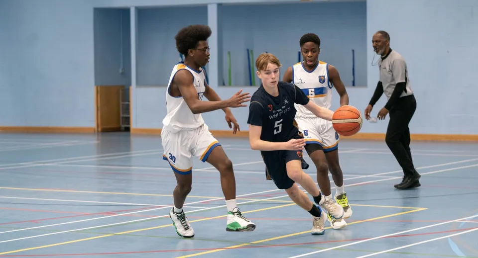 Un gruppo di studenti della Whitgift School gioca a basket sul campo da pallacanestro con la pavimentazione blu.