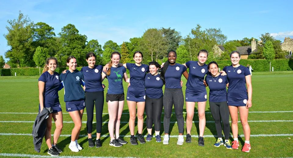 Un gruppo di giovani atlete della Uppingham School è insieme su un prato sotto un cielo blu.