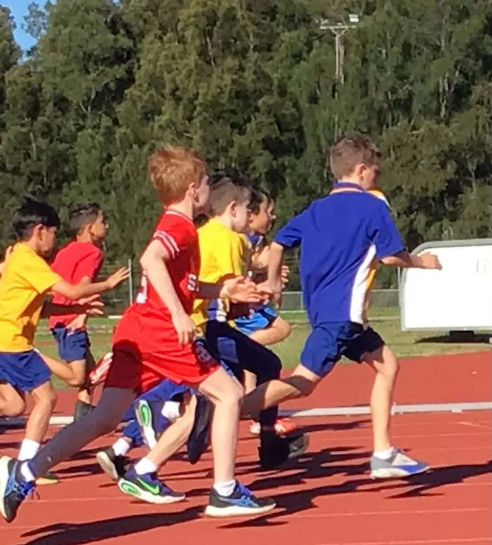 Studenti del Georges River College corrono su una pista di atletica rossa all'aperto.