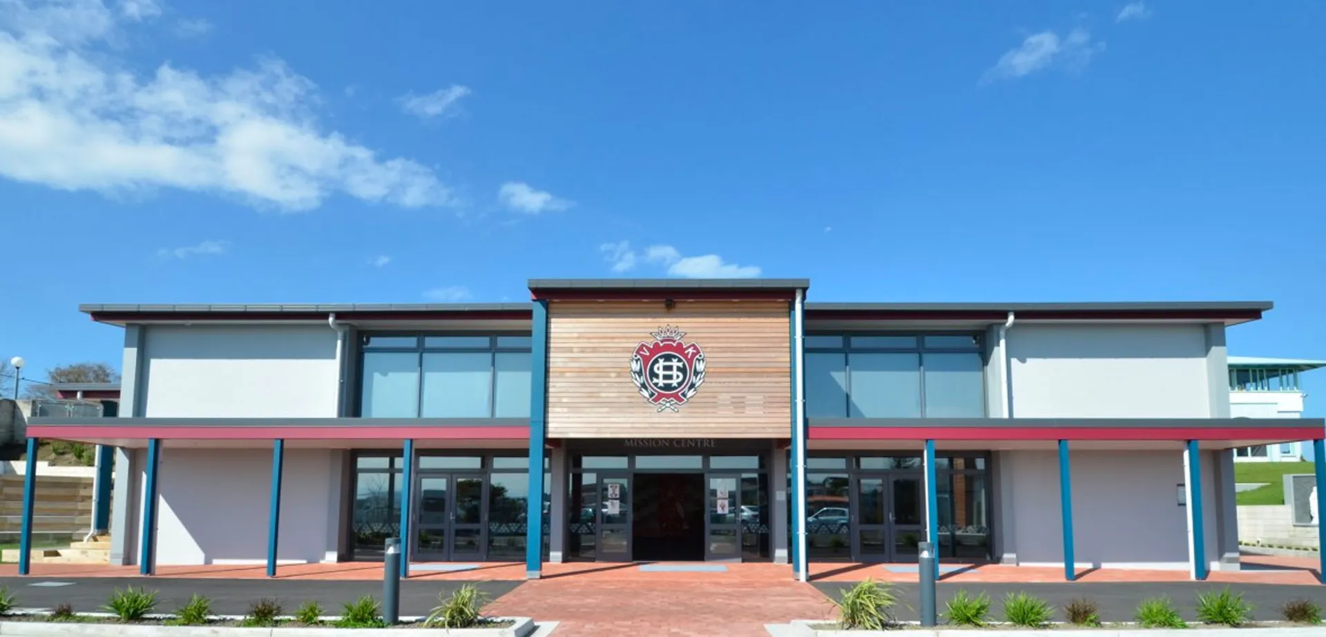 L'edificio moderno a più piani con un grande emblema sulla facciata del Sacred Heart College Napier sotto un cielo azzurro.