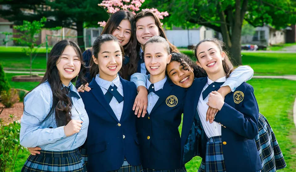 Un gruppo di studentesse della Northern Academy sta all'aperto davanti a ciliegi in fiore.