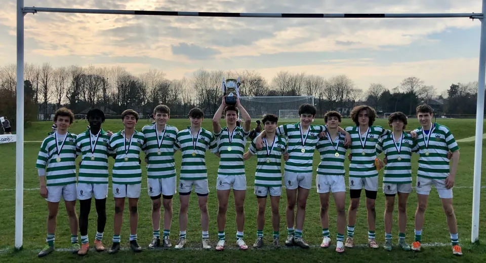 Un gruppo di giovani calciatori tiene la coppa sul campo da gioco del Stonyhurst College dopo una partita.