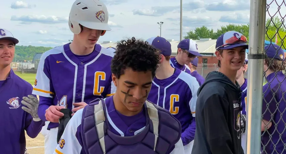 Un gruppo di giovani giocatori di baseball in divisa viola si trova sul campo da baseball della Peoria Christian School.