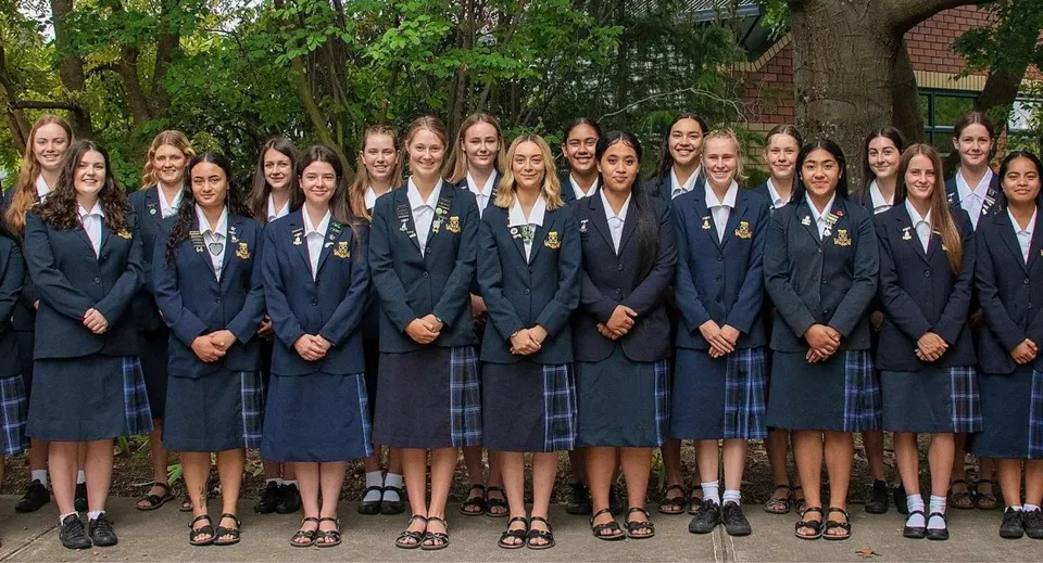 Un gruppo di giovani studentesse della Marlborough Girls si trova insieme in un'area esterna alberata.
