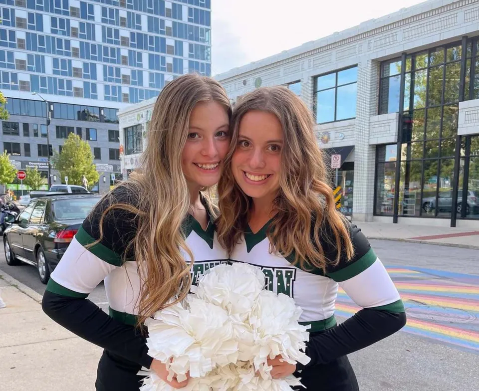 Due studentesse della Jenison High School in posa davanti al moderno edificio scolastico con grandi finestre.