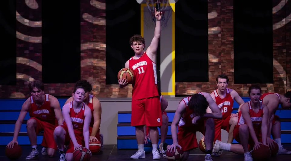 Giocatori di basket della Shirley Boys' High School in maglia rossa durante una partita sul campo da basket.