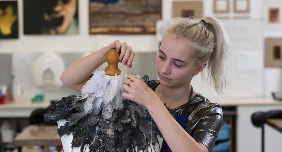 Una studentessa della St. George's School Edinburgh esamina un elemento di costume piumato nello studio d'arte.