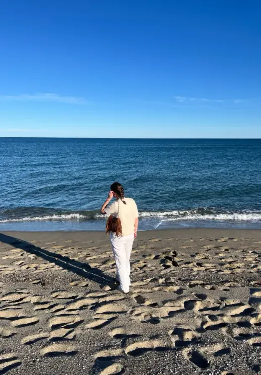 Ragazza di spalle sulla spiaggia guarda il mare in una giornata di sole