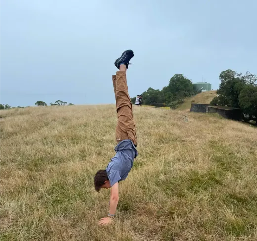 Handstand auf einer hügeligen Wiese in Neuseeland