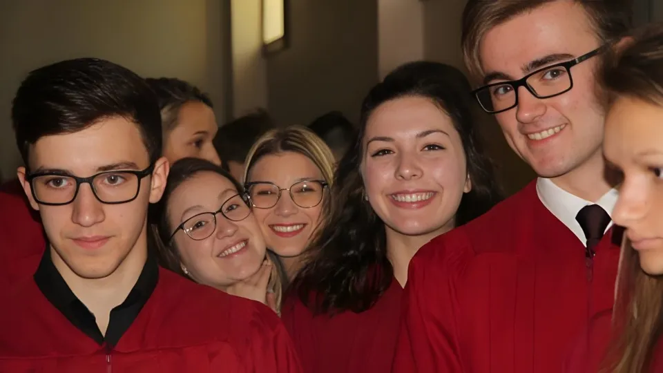 Un gruppo di diplomati in toga rossa posa insieme sul campus della École secondaire Népisiguit.