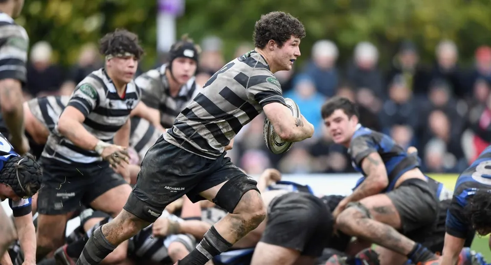Studenti del Christ's College giocano una partita di rugby intensa su un campo erboso davanti a spettatori.