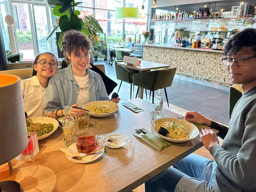 Tre ragazzi sorridenti a tavola al ristorante con piatti di pasta