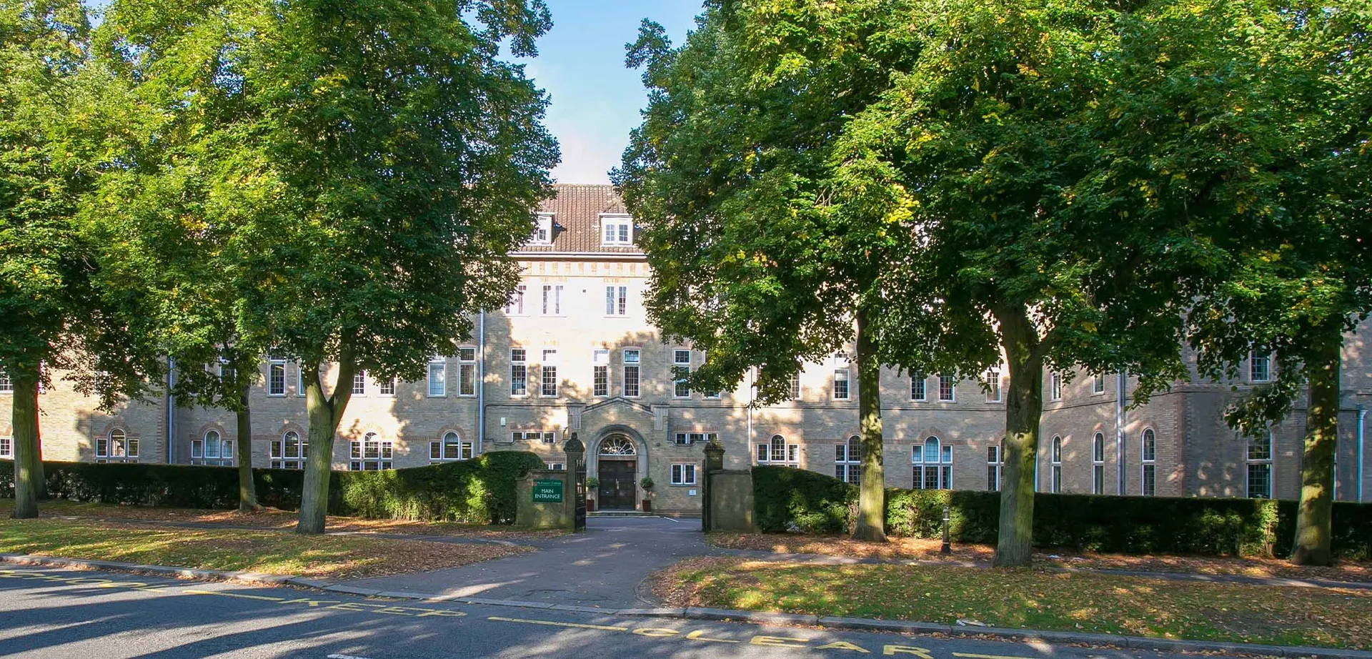 Il campus del St. Francis' College mostra un edificio storico circondato da alberi verdi e da un vialetto pavimentato verso l'ingresso.
