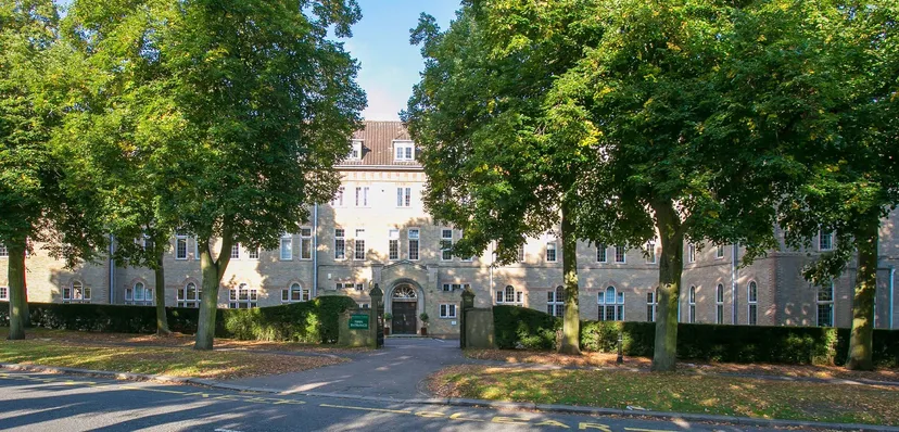 Il campus del St. Francis' College mostra un edificio storico circondato da alberi verdi e da un vialetto pavimentato verso l'ingresso.