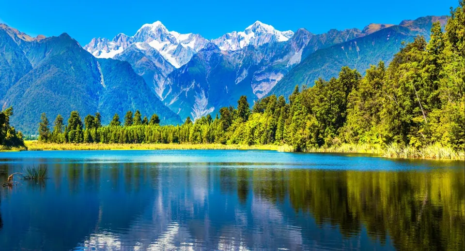 Un lago alpino con montagne innevate e fitti boschi riflette il paesaggio naturale vicino alla Cambridge High School.