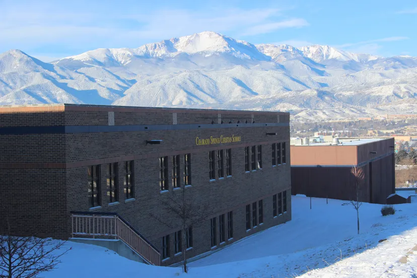 Un moderno edificio a più piani della Colorado Springs Christian School con montagne innevate sullo sfondo.