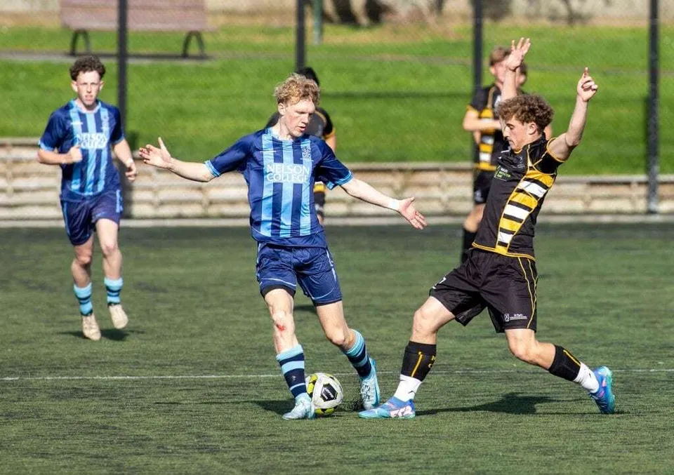 Due calciatori lottano per il pallone sul campo da gioco del Nelson College for Boys.