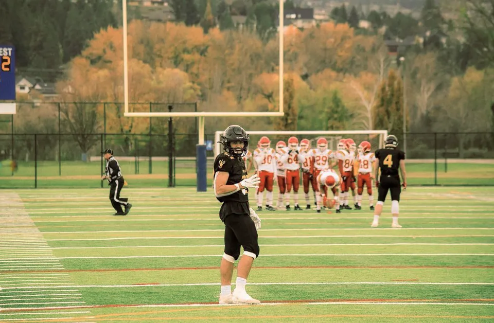 Un giocatore di football americano della Kelowna Secondary School in divisa nera sta sul campo da gioco.