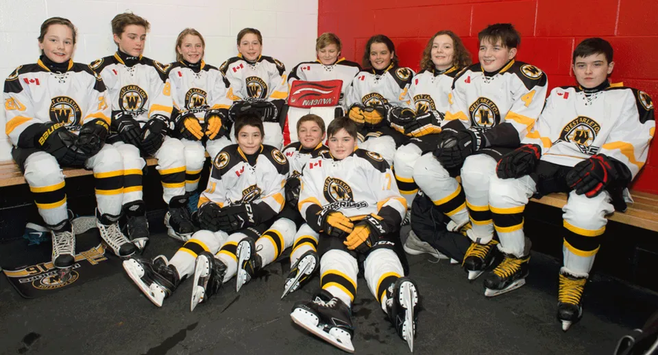 Studenti della West Carleton Secondary School in posa insieme con le loro divise da hockey in un palazzetto del ghiaccio.