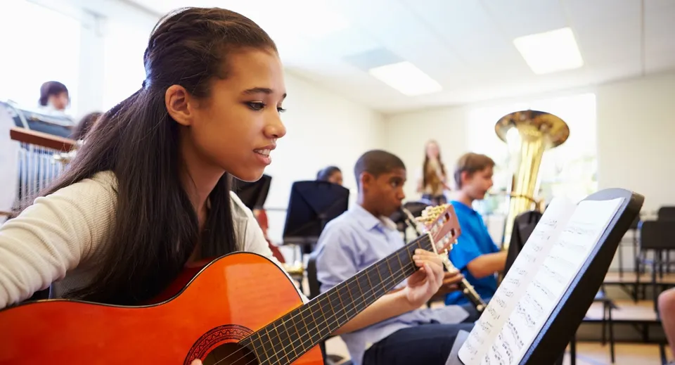 Una studentessa della Gilbert Public Schools suona la chitarra durante la lezione di musica insieme ad altri studenti.