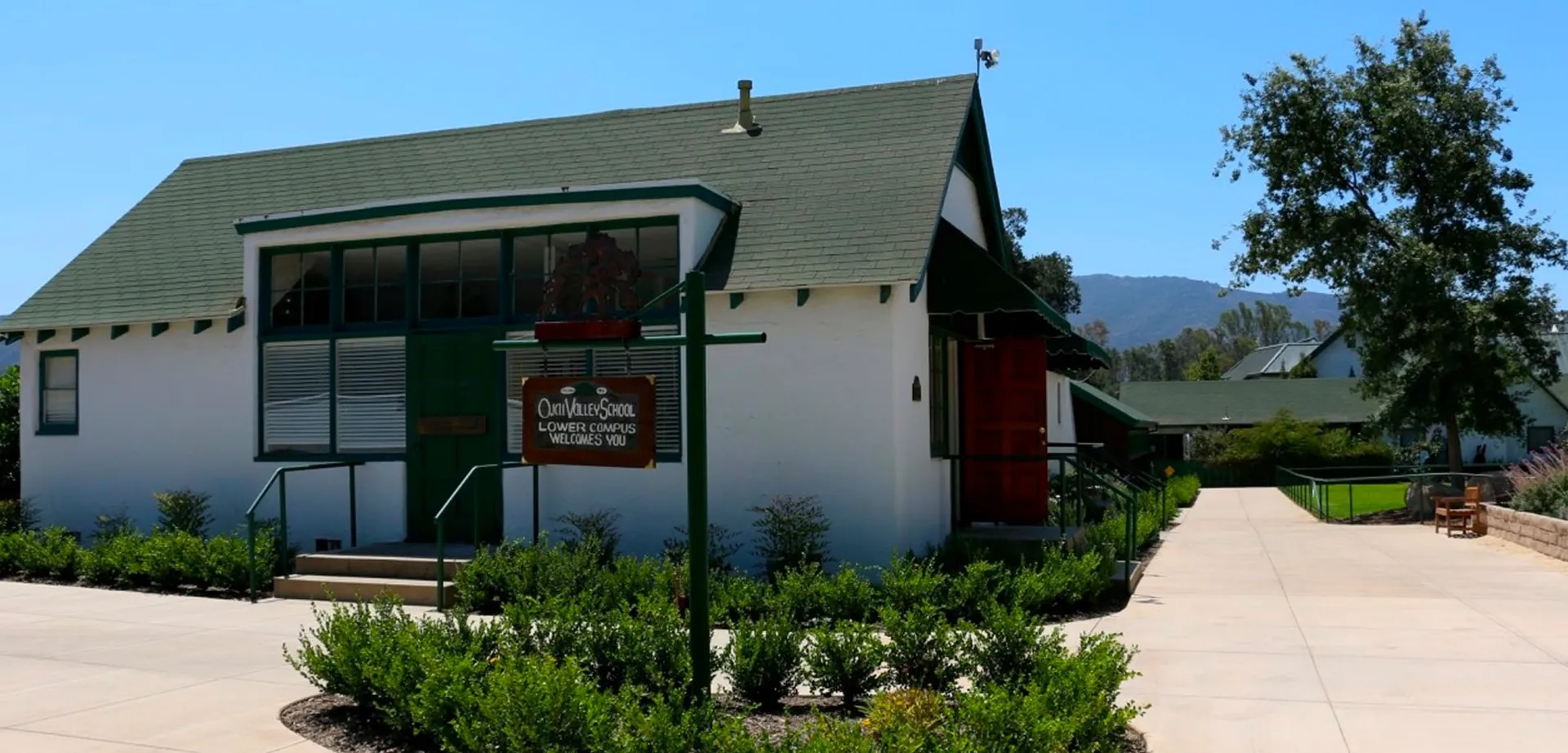 L'edificio dal tetto verde della Carmel Valley Tasting Room nel campus della Ojai Valley School, con montagne verdeggianti sullo sfondo.