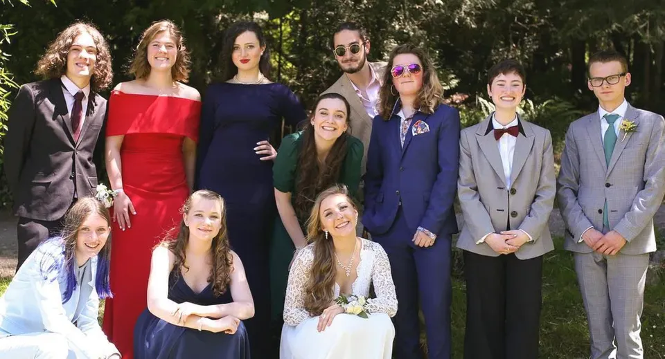 Un gruppo di studenti della Gulf Islands Secondary School posa in abito formale all'aperto davanti ad alberi e verde.
