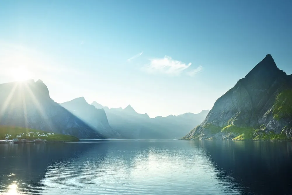 Sonne über einem stillen Fjord zwischen steilen Berggipfeln auf den Lofoten