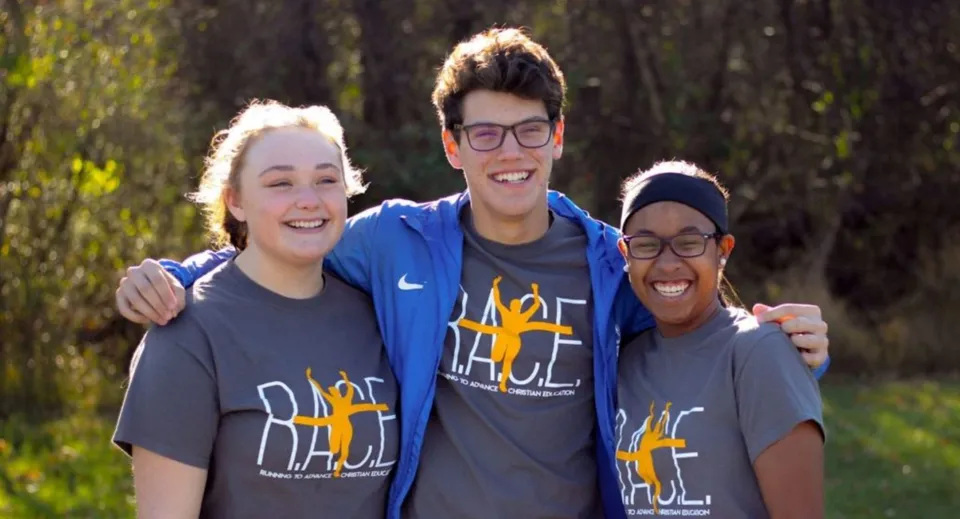 Tre studenti sorridono nel bosco all'interno del terreno della Portland Christian High School.