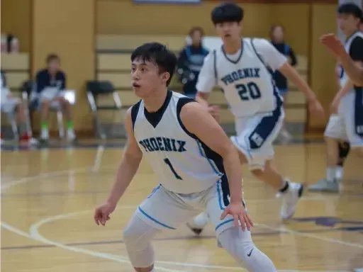 Ein Spieler der Korea International School dribbelt den Basketball während des Spiels auf dem Spielfeld.