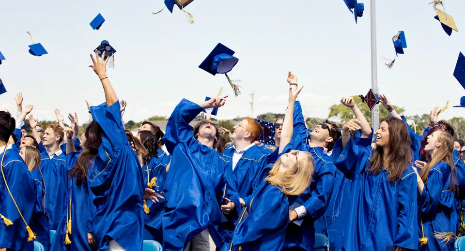 Un gruppo di diplomati della Malanda State High School lancia i propri cappelli blu in aria.
