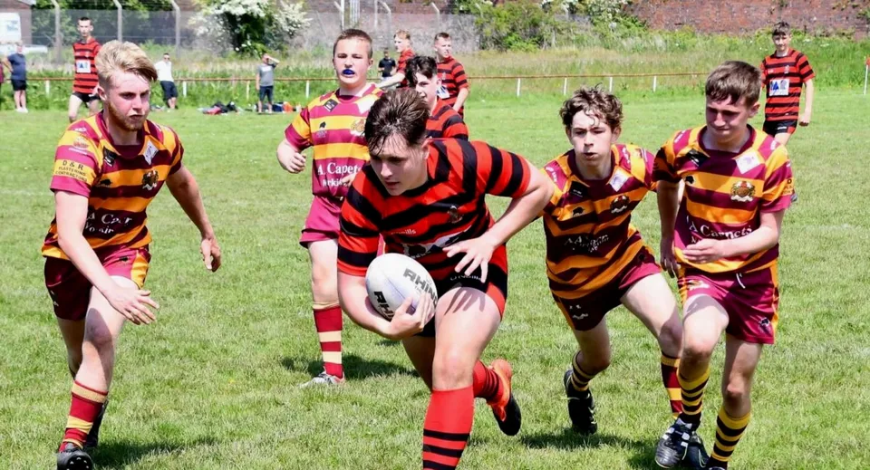 Un gruppo di giocatori di rugby corre sul campo sportivo del Lord Wandsworth College durante una partita.
