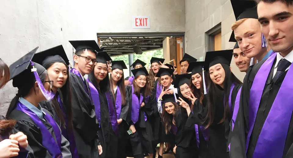 I neo-diplomati della University Hill Secondary School sono riuniti in un corridoio indossando toghe viola.