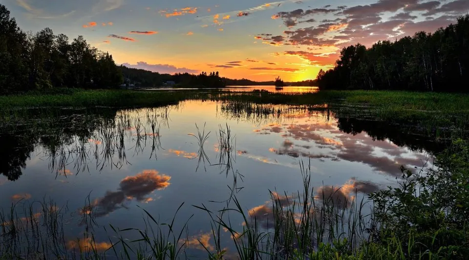Tramonto su un lago calmo con sponde alberate vicino alla Thomas A. Blakelock High School.