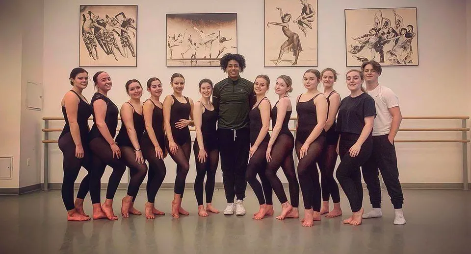 Un gruppo di giovani ballerine e ballerini dell'East Sussex College Eastbourne è in una sala di danza davanti a una sbarra.