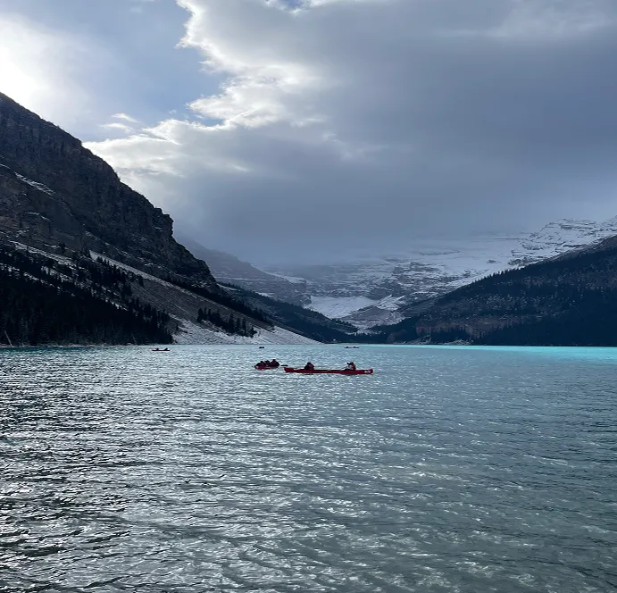 Lago de montaña de aguas turquesas con canoas y cumbres nevadas al fondo en Canadá