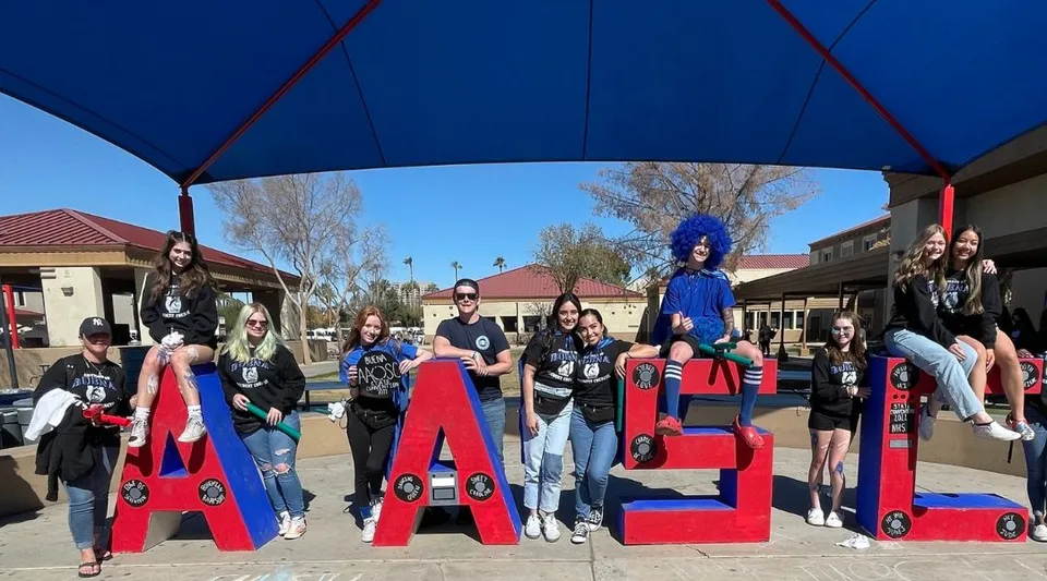 Un gruppo di studentesse e studenti in costumi colorati posa davanti a grandi lettere rosse con la scritta CASA nel Sierra Vista Unified School District.