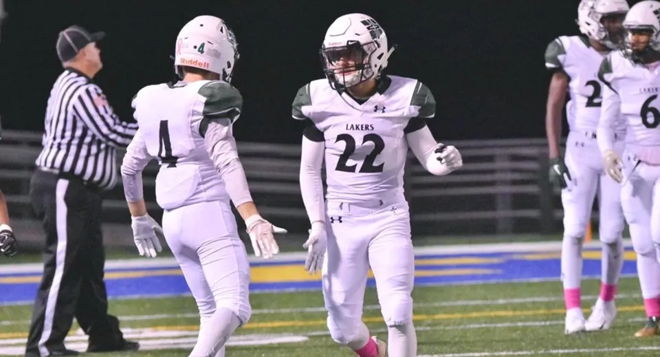 Giocatori di football americano della Erie First Christian Academy con divise bianche sul campo da gioco durante una partita.