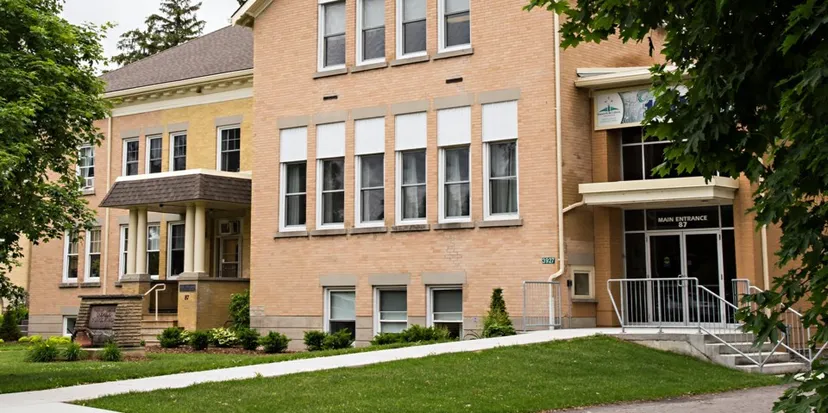 L'edificio in mattoni a più piani del Huron-Perth Catholic District School Board è circondato da un prato ben curato e da alberi.