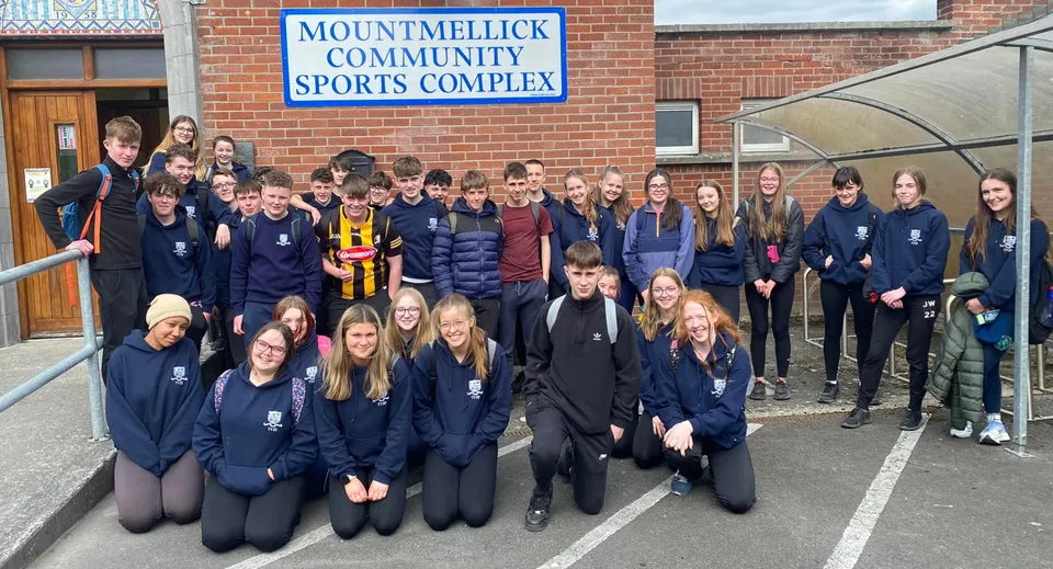 Un gruppo di studenti e studentesse sta davanti all'edificio del Mountmellick Community School Sports Complex.