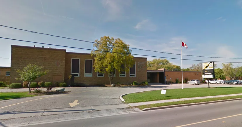 L'edificio in mattoni della Tilbury District High School con una bandiera canadese su un pennone e alberi tutt'intorno.