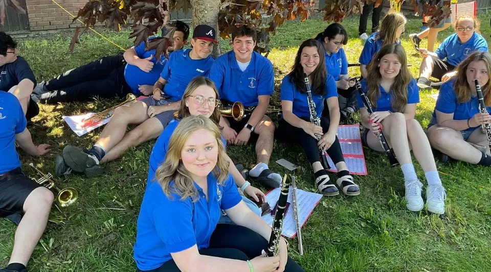 Un gruppo di studentesse e studenti della Pasadena Academy si trova all'aperto su un prato davanti agli alberi.