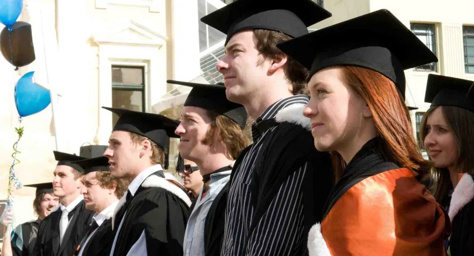 Un gruppo di diplomati in toga festeggia il proprio diploma alla Centre Wellington District High School.