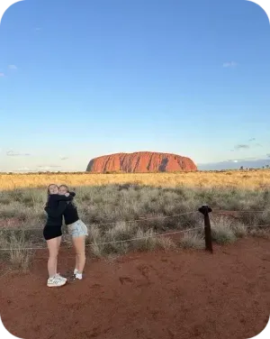 Due ragazze si abbracciano davanti a Uluru nell'outback australiano.
