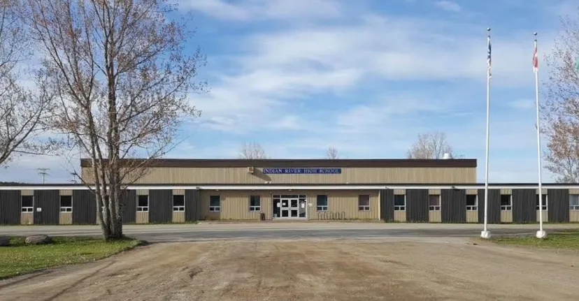 Il grande edificio scolastico marrone della Indian River High è circondato da alberi e da un prato.
