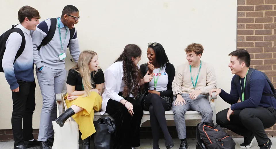 Un gruppo di studenti della Theale Green School siede insieme in un'aula con pareti in mattoni a vista e chiacchiera.