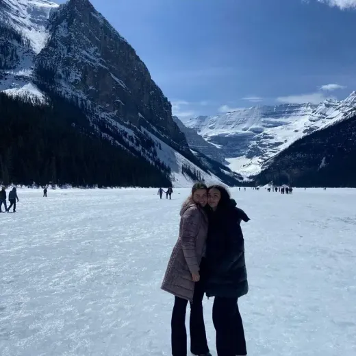 Dos chicas se abrazan en un lago helado entre montañas nevadas de Canadá